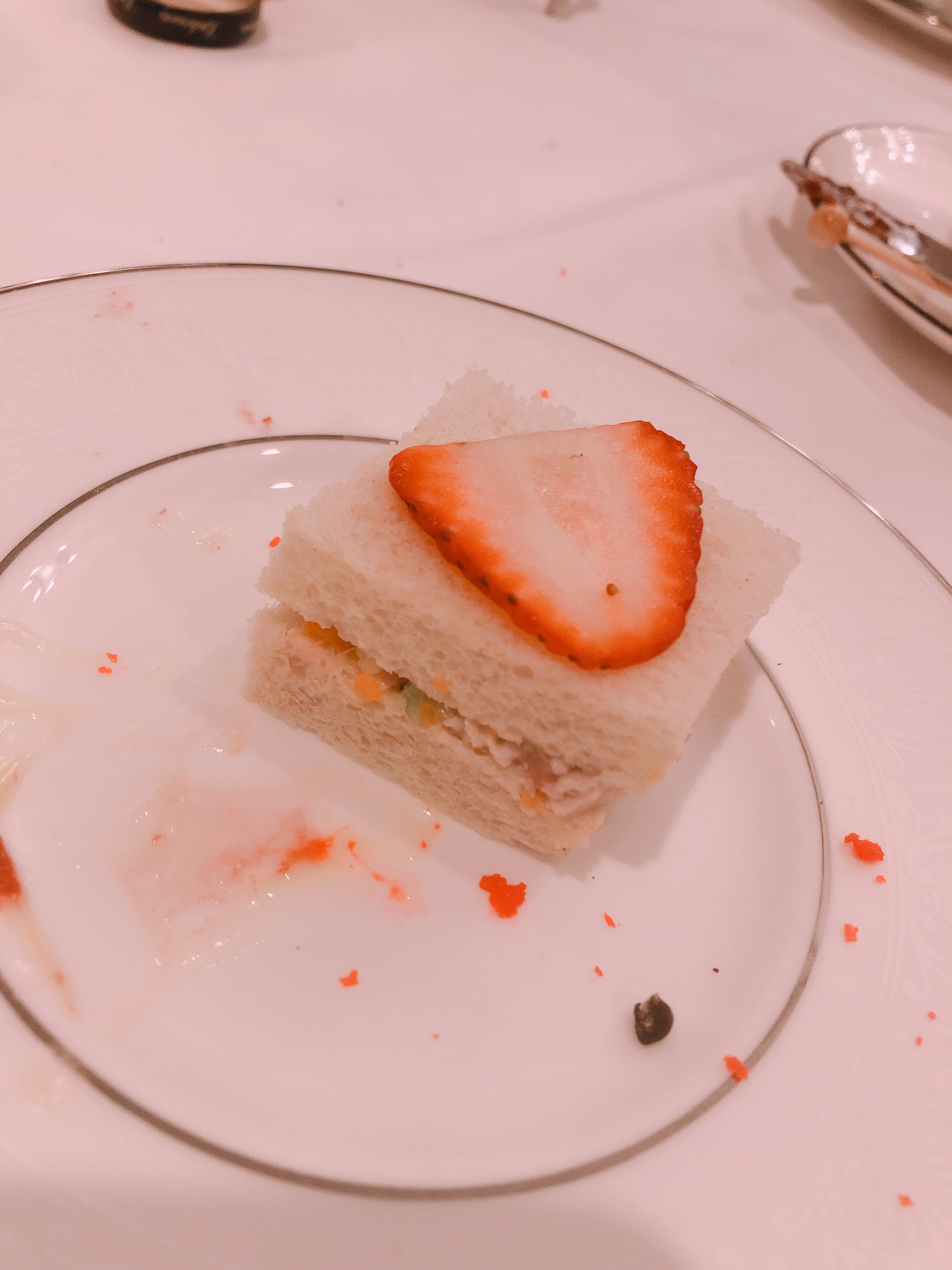 a picture of a strawberry chicken salad sandwich. teas-size, white bread with a prominent strawberry slice on top.